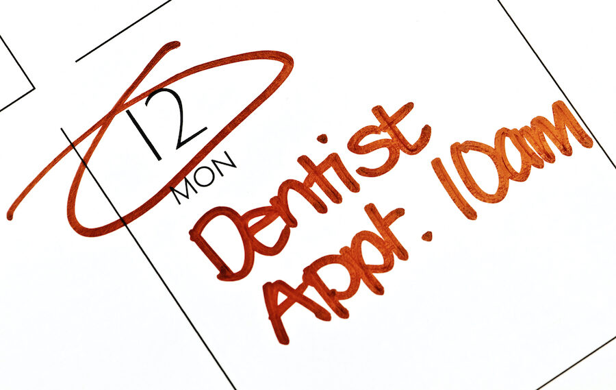 closeup of a calendar square with a reminder in red writing about a scheduled dentist appointment